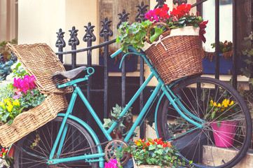 Fototapeta na wymiar Vintage blue bicycle with flower baskets, on a city street