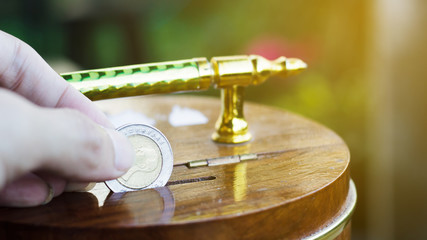 Hand holding coin drops into a wooden piggy bank. Saving coin concept. Conceptual saving money for business or life in future. Concept saving money background for web banner. Investment money Concept.