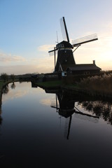 Dutch windmill in evening sun reflects in water