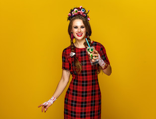 smiling woman on yellow background with Halloween cocktail