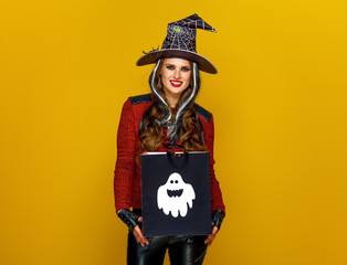 happy woman isolated on yellow with Halloween shopping bag
