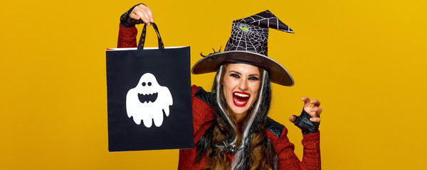 smiling modern woman showing shopping bag and frightening