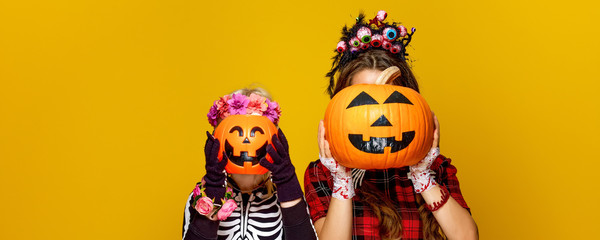 mother and child holding jack-o-lantern pumpkins in front of faces