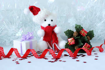 ourson polaire portant un bonnet et une écharpe rouge posé à coté de cadeaux pour décoration de fêtes de Noël