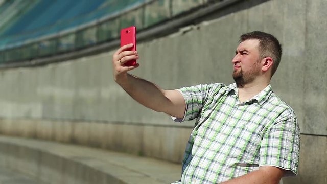 Businessman makes selfie on his smartphone. Man makes photos on cell phone