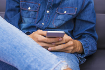 young hands with mobile phone and blue denim clothing