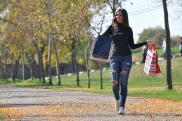 Girl walking after shopping and speak on phone. Woman carrying bags after shopping and talk on mobile