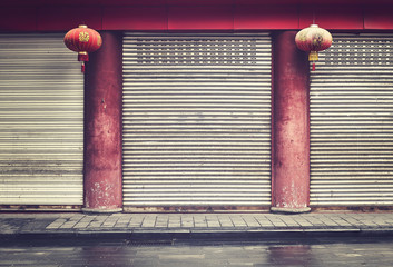Closed shops facade with red columns and lanterns, color toning applied, China.