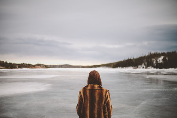 girl observing the scene of the frozen lake & winter landscape.