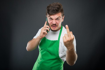 Supermarket employer talking at phone showing obscene gesture