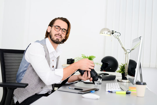 male photographer editing photography in office with a computer, camera and graphic tablet