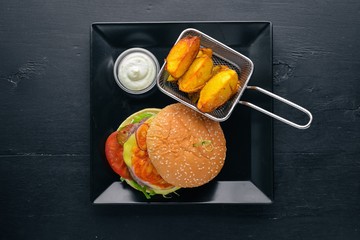 Burger and potatoes with sauce. On a wooden background. Top view. Free space for your text.