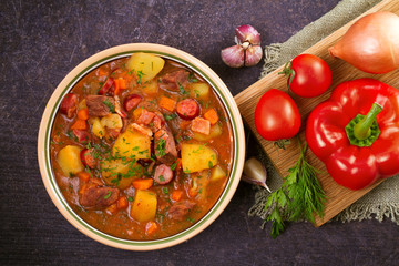 Tasty stew. Goulash soup bograch in a bowl and ingredients. Hungarian dish, view from above, top shot, horizontal