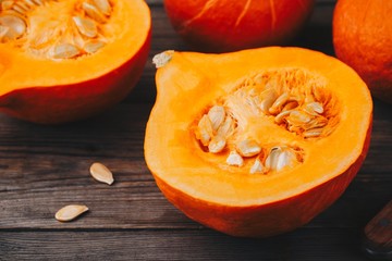 raw pumpkin slices with seeds on a wooden background.