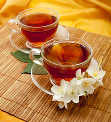 Tea in a glass cups with jasmine flowers on bamboo mat.