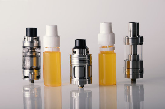 isolated vape tanks and e liquid for electronic cigarette or e cig over a white background. vaping rdta and e juice for vaping devices.