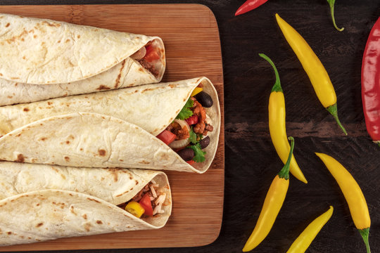 Mexican burritos with chili peppers on dark textures