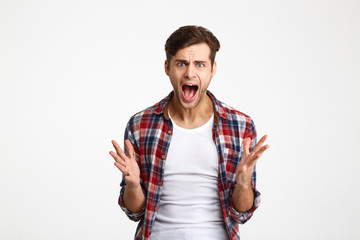 Close-up portrait of young emotional screaming man standing with opened palms, looking at camera