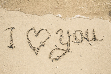 The inscription on the sand near the sea and the waves - I love you. Background.