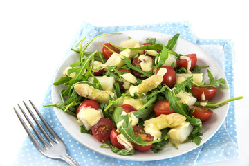 mixed salad of white asparagus, cocktail tomatoes and arugula, appetizer snack on a blue napkin, white background, copy space