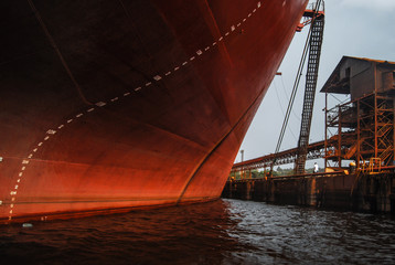 Prow of an old red freighter at wharf