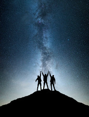 Silhouettes of team on mountain peak. Sport and active life concept on the night sky background.
