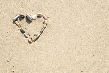 Fototapeta na wymiar Heart shape made of different shells on sand