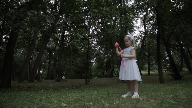 Little girl blows soap bubbles in the park