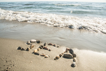 The inscription of the sea with stones on the sand with sea waves
