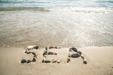 Fototapeta na wymiar The inscription of the sea with stones on the sand with sea waves