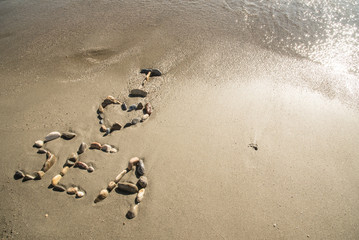 The inscription made of different shells on the sand near the sea and the waves - I love sea. Background.