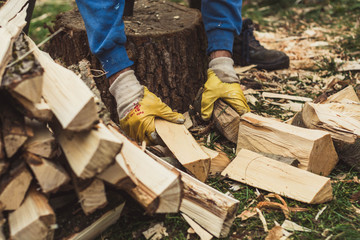 Man picking up chopped firewood.