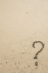 Question mark sign on sand beach near the sea and waves