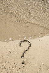 Fototapeta na wymiar Question mark sign on sand beach near the sea and waves