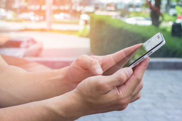 Close up of men hands holding touching mobile phone with blank copy space for your text message at park with light Sunset,Vintage tone.Selective focus