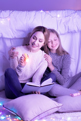 Loving mother and daughter hugging while reading