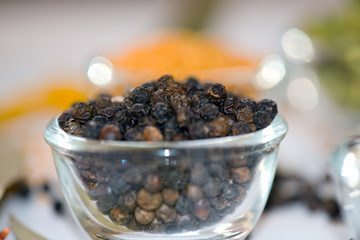 A close-up shot of whole black peppercorns in a glass bowl, highlighting their dark, wrinkled texture. A staple spice in global cuisine, known for its bold, pungent flavor and aromatic depth