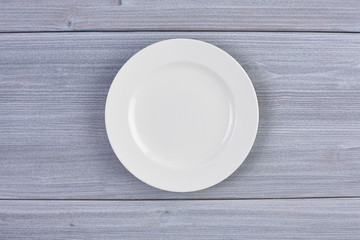 Top view of clean white dish on background of wooden table