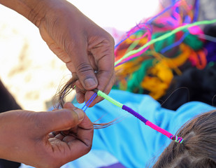 hand of African woman interlaces the hair of a little girl with