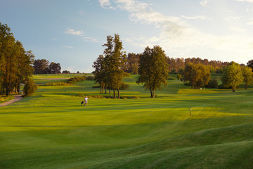 man with his son golfers walking on perfect golf course at summer evening