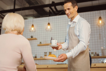 Joyful positive waiter serving breakfast