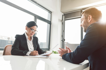 Glad career girl speaking with beaming colleague