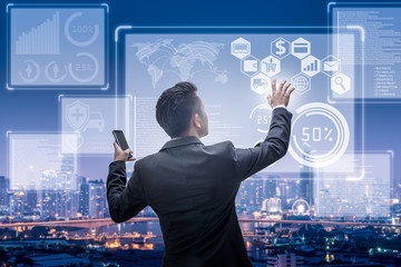 The abstract image of business man point to the hologram on the rooftop and blurred cityscape is backdrop. the concept of communication, network, business, cyber, economy and internet of things.