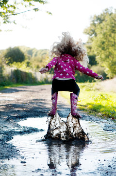 Girl jumping in a muddy puddle
