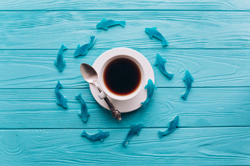A cup of coffee on a wooden blue background with fish. - Powered by Adobe