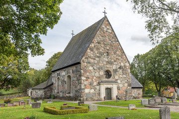 Fototapeta na wymiar Össeby-Garns vackra stenkyrka i Roslagen sett från långsidan med huvudingången