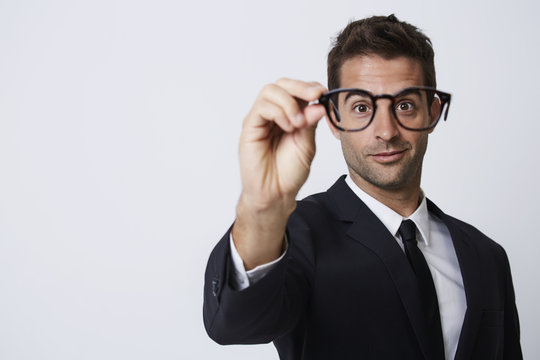 Businessman holding spectacles up to camera, smiling
