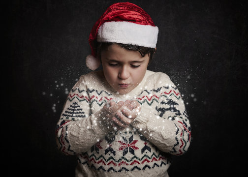 ni&ntilde;o soplando la nieve en navidad   