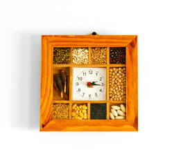 Natural handmade clock with seeds on white background.