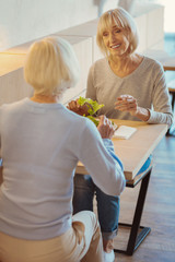 Happy delighted women sitting opposite each other